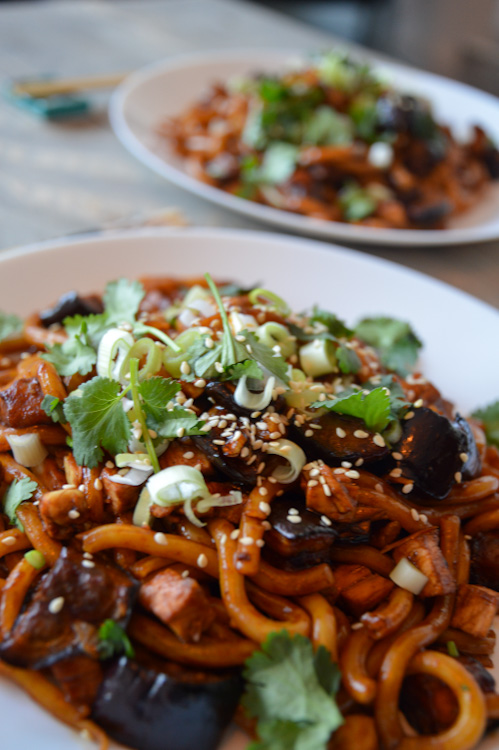 Close up of two plates of our take on yaki udon: udon noodles with miso roasted eggplant