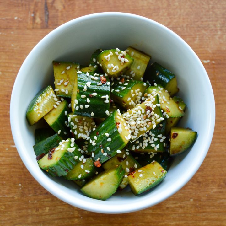 White bowl of Sichuan cucumber salad with sesame seeds