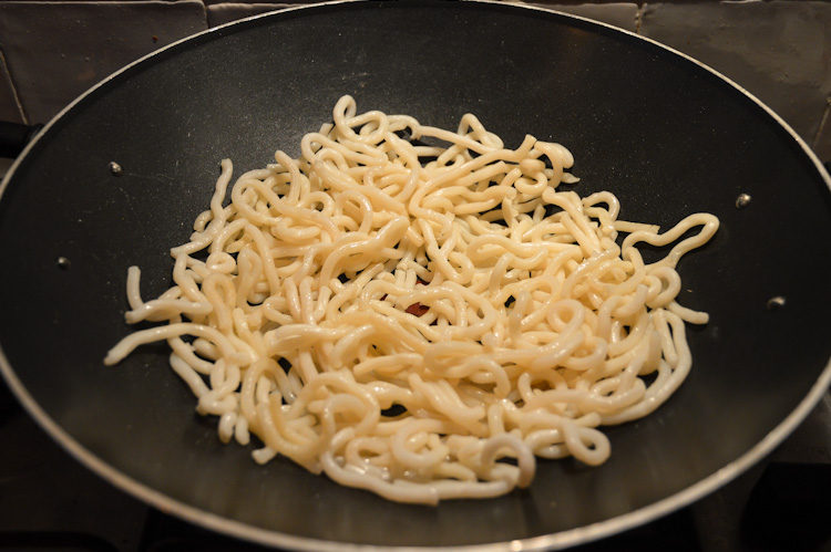 Udon noodles cooking in a wok