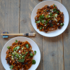 Two plates of udon noodles with miso roasted eggplant and chopsticks on a table