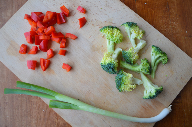 Red pepper, broccoli, and green onion on a cutting board