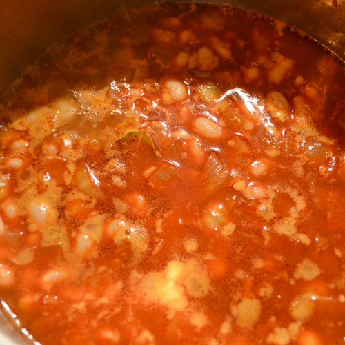 A red liquid with beans cooking in a pot