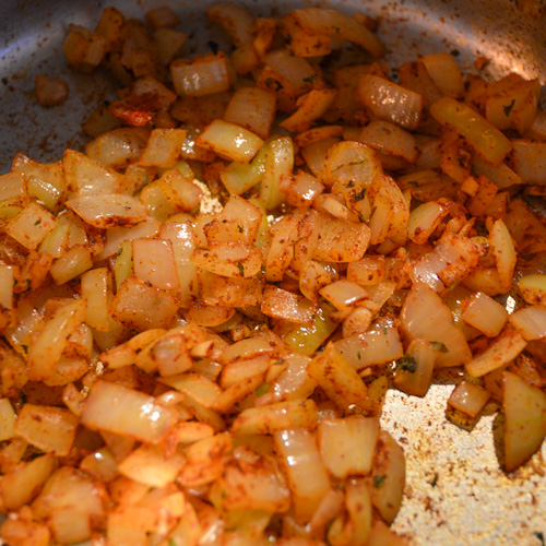 Onions, garlic, and spices cooking in a silver pot