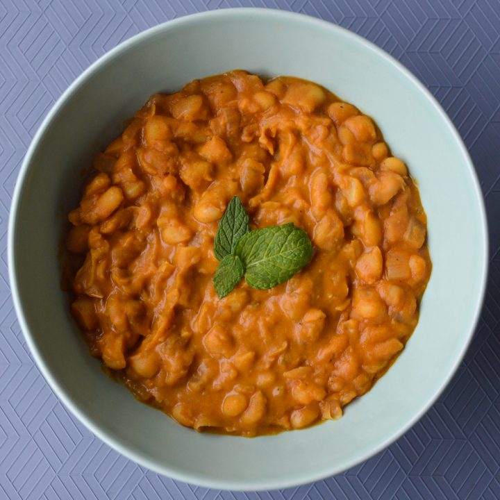 Tavce gravce inspired Macedonian beans - creamy orange colored beans in a bowl topped with a few mint leaves