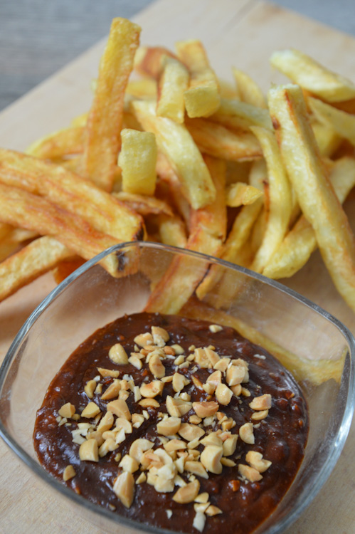 Close up of pindasaus (Dutch peanut sauce) with french fries on a wood board