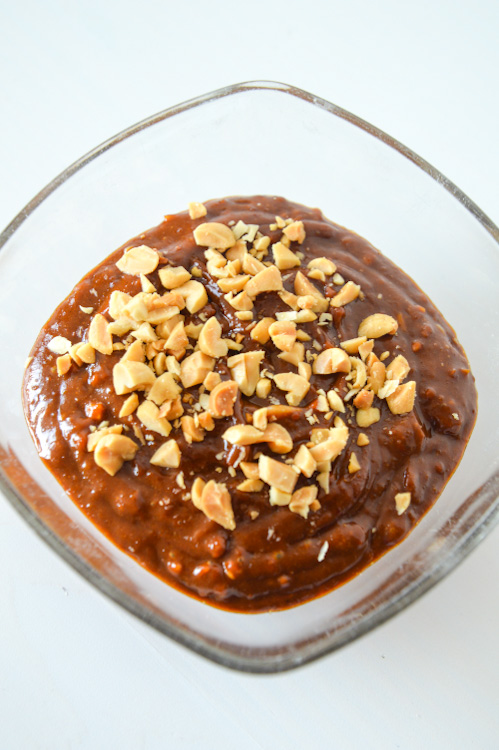 Glass bowl of pindasaus (Dutch peanut sauce) against a white background