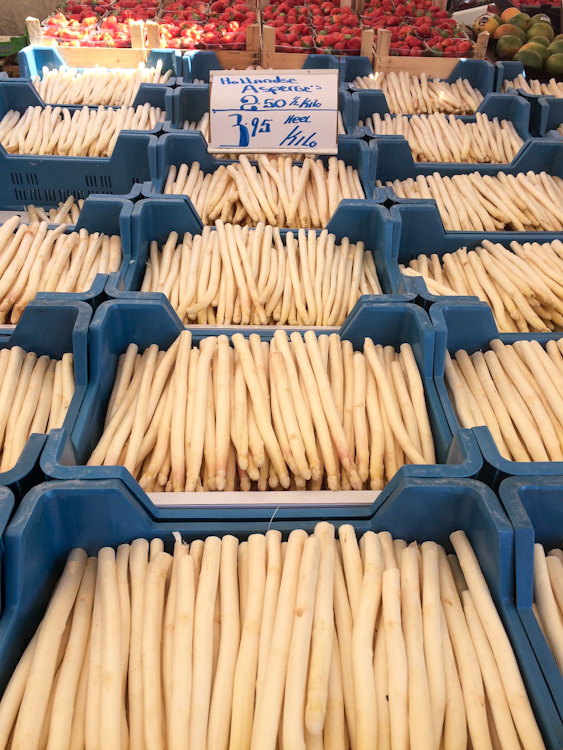 White asparagus in blue bins at an outdoor market