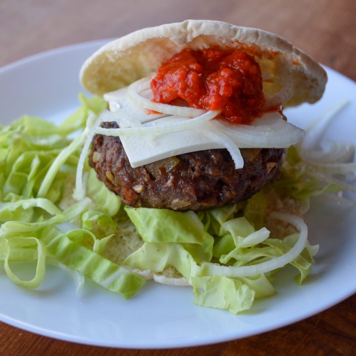 Our Balkan Burger on a plate surrounded by cabbage and onions