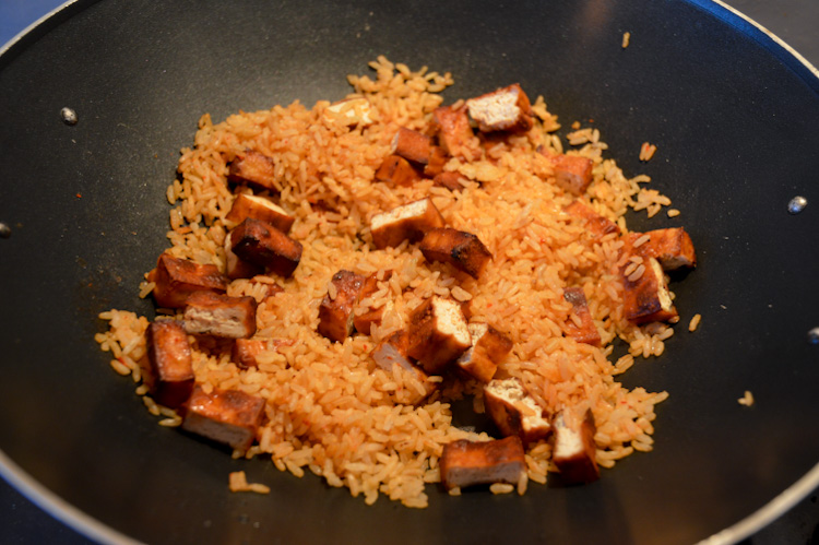 Brown rice and pieces of tofu cooking in a wok