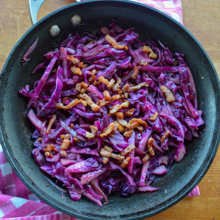 Square picture of sautéed red cabbage topped with bacon lardons in a pan