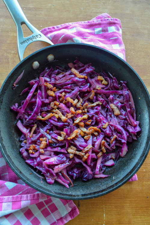 Sautéed red cabbage with crispy bacon lardons on a pink and white towel