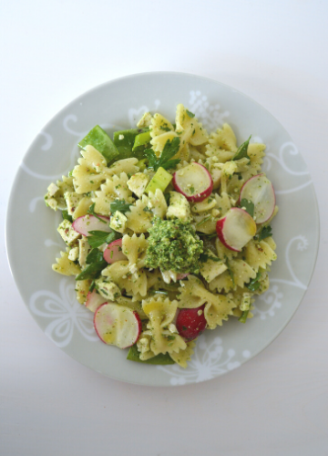 A plate of pasta salad with radish greens pesto on a white table