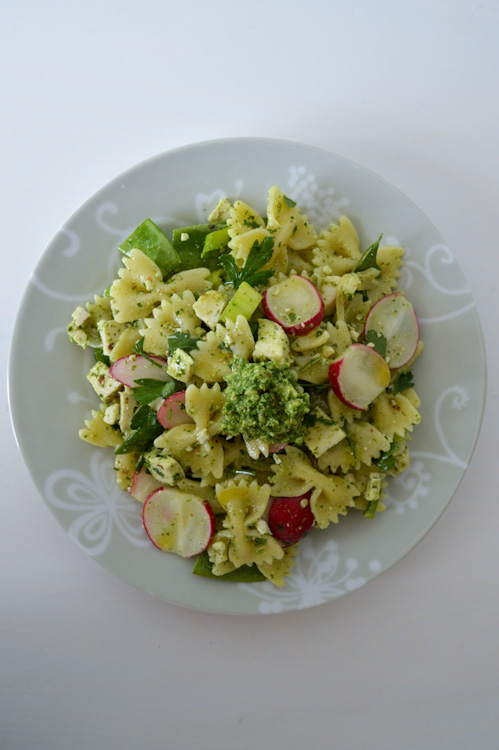 Small plate of pasta salad with radish greens pesto on a white table