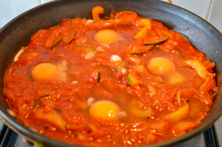 Four eggs nestled in a tomato stew in a pan