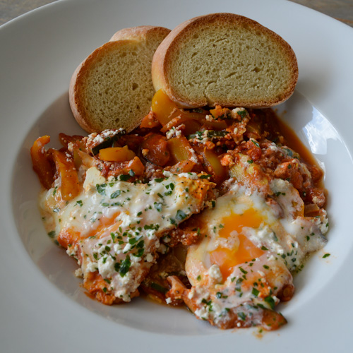 Shakshuka for two in a bowl with runny eggs and toasted bread