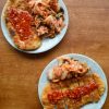 Two plates of Korean tonkatsu with gochujang sauce served with sides of kimchi on a brown table