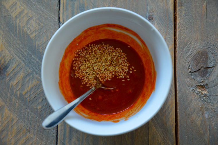 Red gochujang sauce with sesame seeds in a white bowl