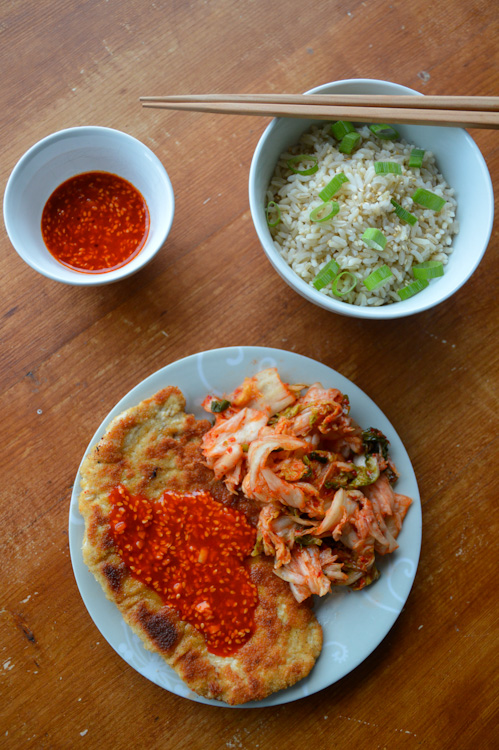 3 dishes on a table: small bowl of gochujang sauce, slightly larger bowl of rice with chopsticks, plate of Korean tonkatsu with kimchi