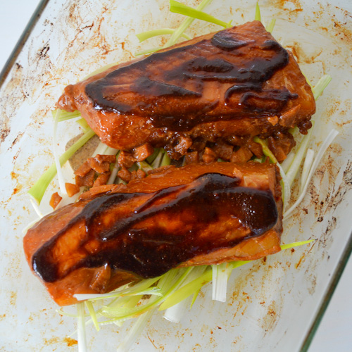 Two cod fillets in a baking dish topped with brown glaze