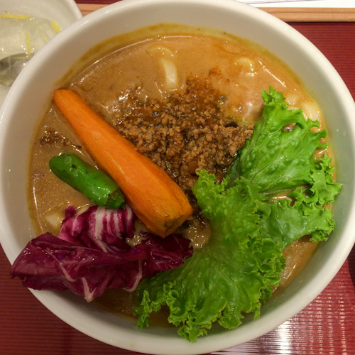 Bowl of Japanese curry udon with ground beef, lettuce, and a large carrot