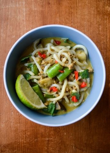 Blue bowl of curry udon soup with a lime wedge