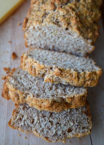 Sliced loaf of whole wheat beer bread on a wood board