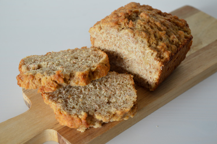 Half a loaf plus two slices of whole wheat beer bread on a small wood board