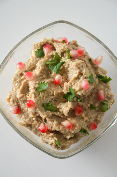 Eggplant pkhali in a small glass bowl with pomegranate seeds and cilantro