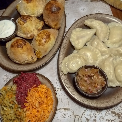 Table with two plates of pierogis and a side of Polish salads