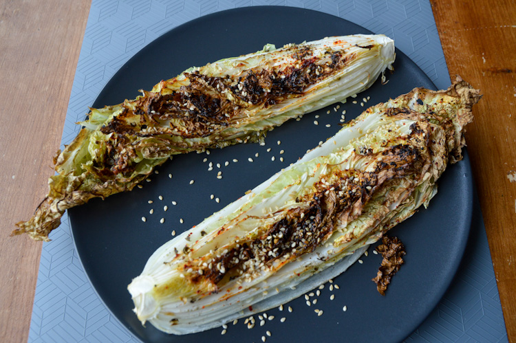 Angled view of two pieces of roasted napa cabbage with sesame seeds