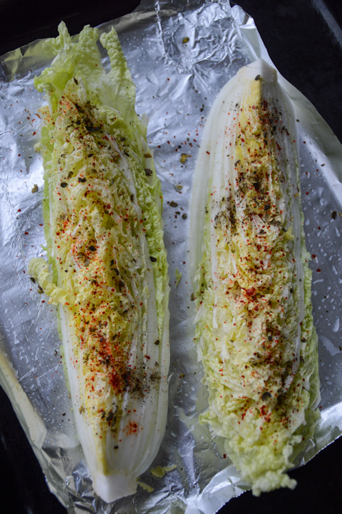 Top down view of Two pieces of cabbage on aluminum foil being prepped to be roasted