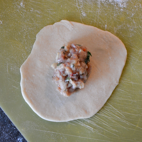 A small circle of rolled out dough with a Tbsp of khinkali meat mixture in the center