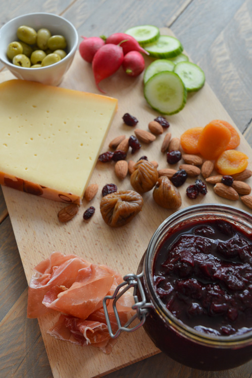 A wood board with everything you'd want: meat, cheese, nuts, dried fruit, olives, veg, and of course a jar of plum chutney