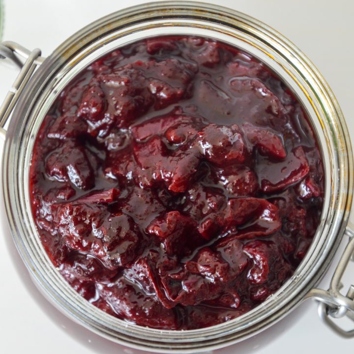 Top down view of glass jar with deep purple spiced plum chutney