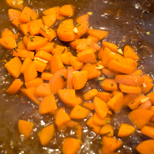 Small pieces of carrots atop stoofvlees, a dark brown, thick beef stew