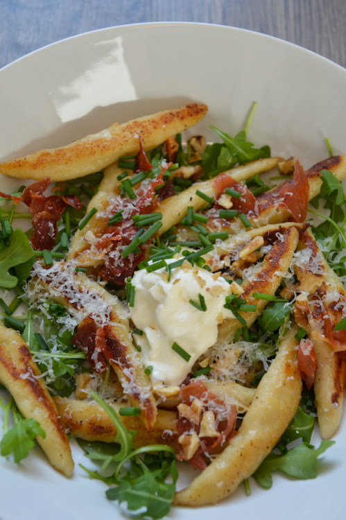 Schupfnudeln with arugula and other tasty toppings in a white bowl