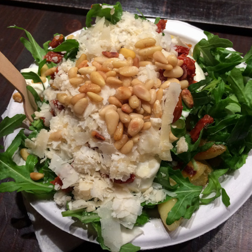 A bowl of Schupfnudeln with arugula, parmesan cheese, and pine nuts eaten at a Christmas Market in Cologne