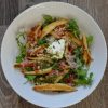 White bowl full of Shupfnudeln (German potato dumplings) plus arugula and other tasty toppings