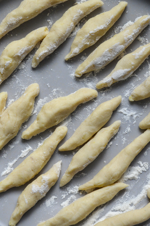 Formed German potato dumplings (Schupfnudeln) on a grey plate, dusted with a little flour