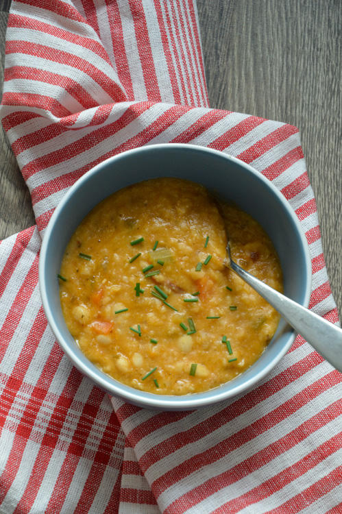 Bowl of vegan white bean soup - a spoon stuck in ready to eat