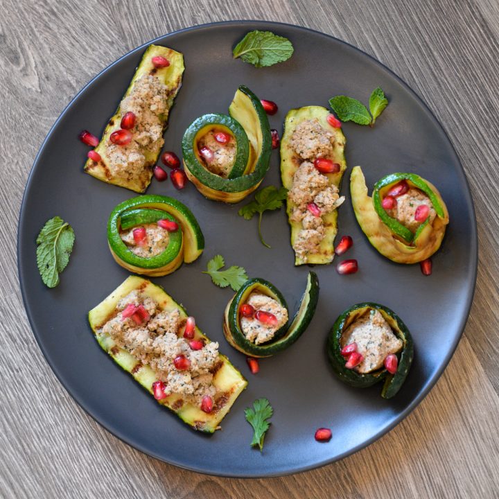 Black plate with 3 pieces of zucchini topped with Georgian walnut paste and 5 zucchini spirals with the paste in the center