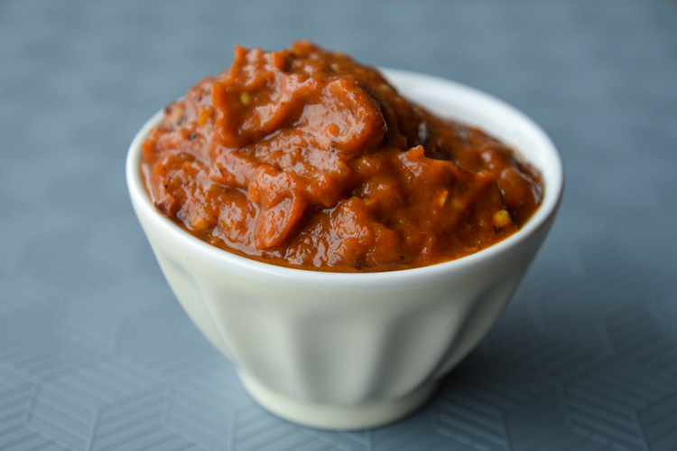 A small white bowl of zacusca (roasted red pepper and eggplant spread)