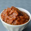 Small white bowl holding a nice amount of red pepper, eggplant spread (aka zacusca)