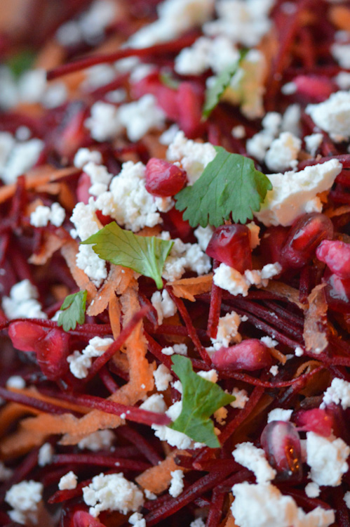 Super close shot of a beetroot salad with feta, carrots, pomegranate seeds, and parsley