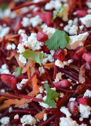Very close shot of a beetroot salad with feta, carrots, pomegranate seeds, and parsley