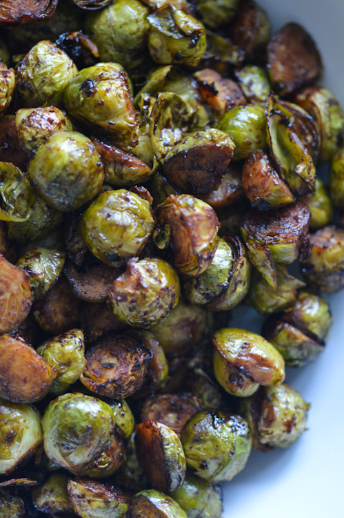 Close up of roasted brussels sprouts with soy sauce, hoisin, and sesame oil in a white bowl