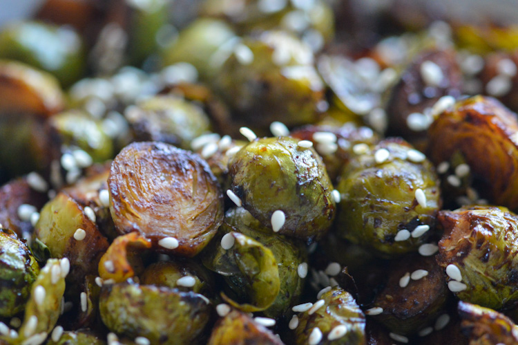 A super close shot of nicely browned roasted brussels sprouts topped with sesame seeds