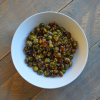 A white bowl of roasted Brussels sprouts sitting atop a wooden table