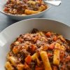 Two bowls of Korean beef stew with tubular rice cakes and carrots, one clear in the foreground, one a bit blurred in the background