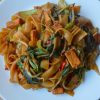 White plate full of vegetarian drunken noodles - wide rice noodles with tofu